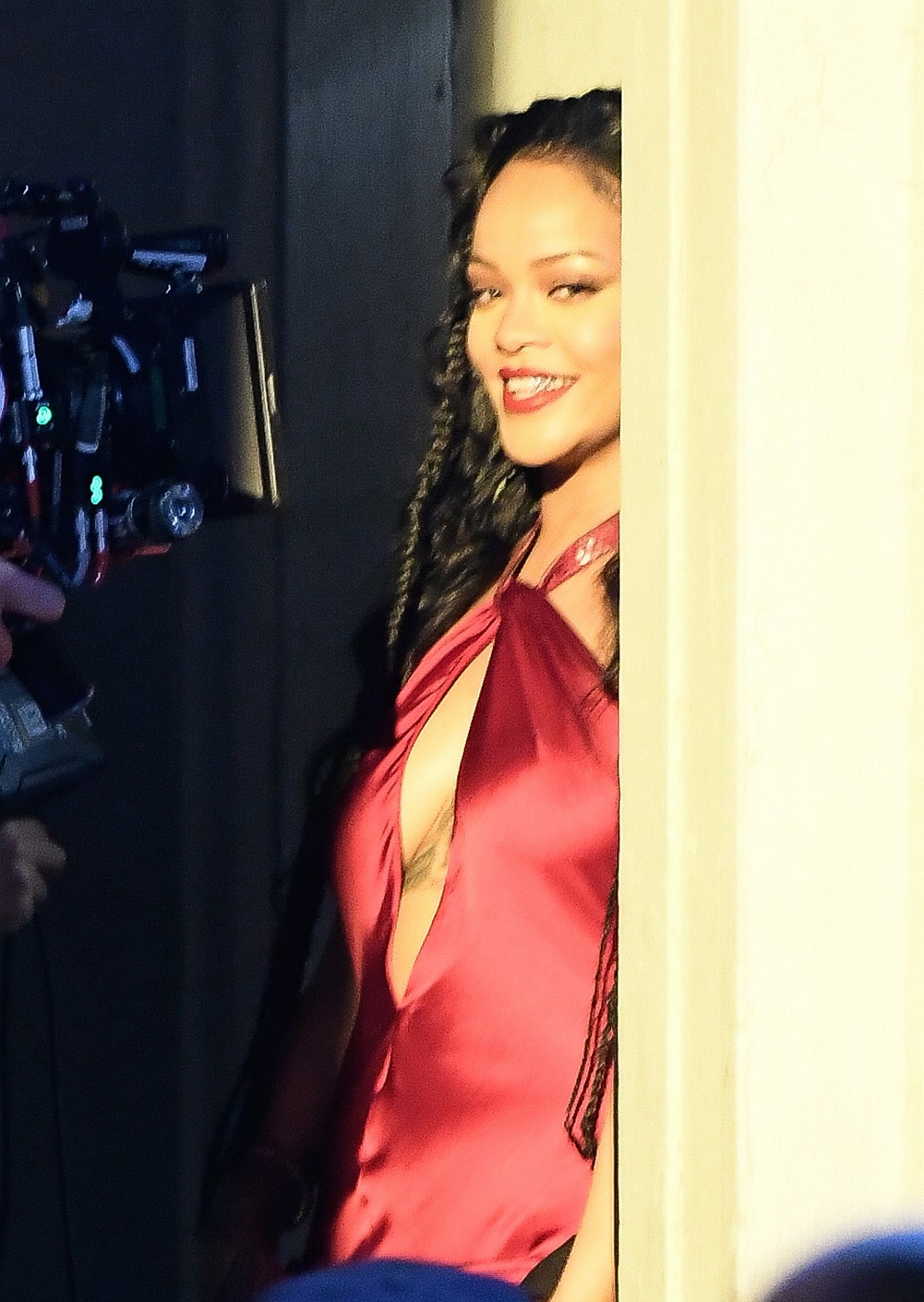 Rihanna în timp ce se sprijină de un perete într-o rochie roșie și este filmată pentru noul său videoclip muzical cu A$AP Rocky