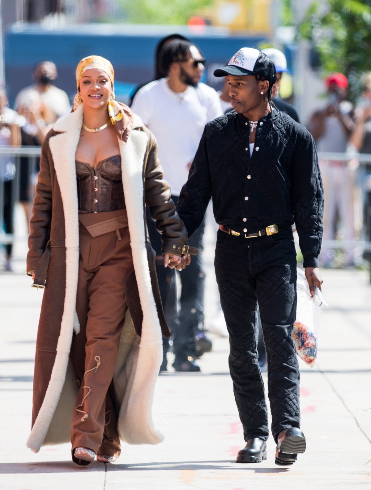 Rihanna într-o ținută monocromatică crem cu palton de iarnă și un batic galben pe cap în timp ce-l ține de mână pe iubitul său A$AP Rocky după ce au filmat împreună un nou proiect