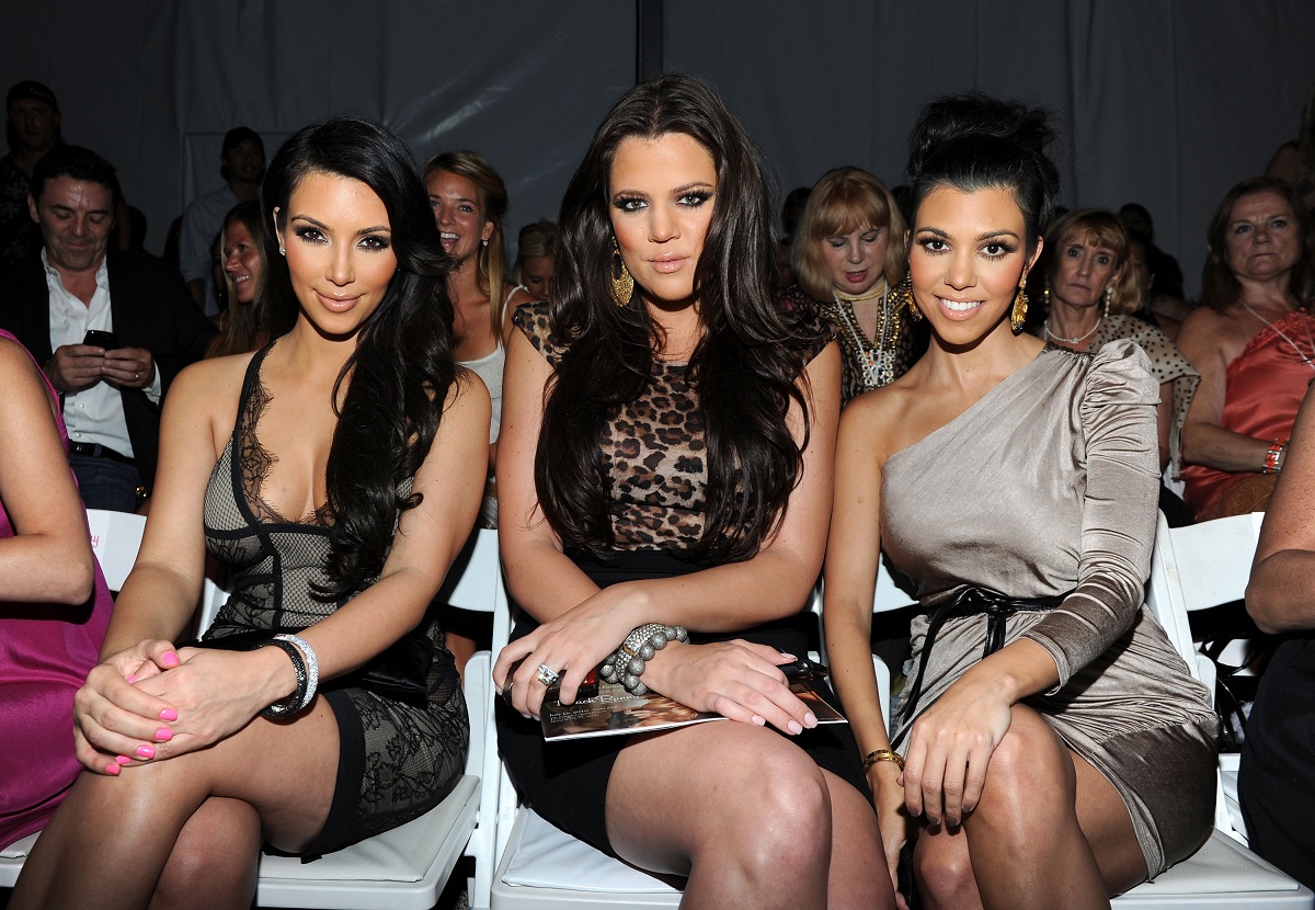 Surorile Kardashian, Kim Kardashian, Khloe Kardashian și Kourtney Kardashian în timp ce stau pe scaune și sunt îmbrăcate elegant la un eveniment public din anul 2014