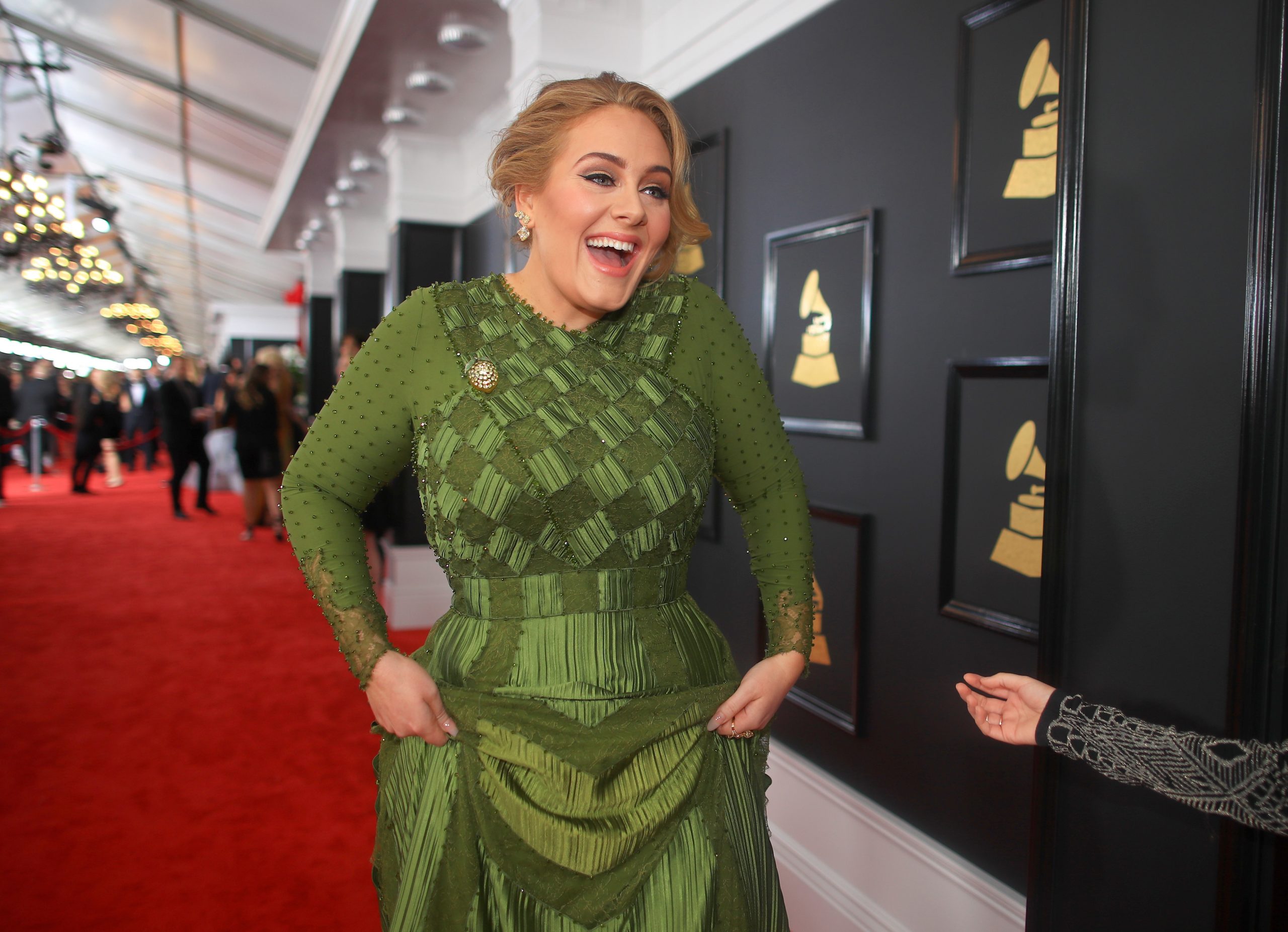 Adele pe covorul roșu la cea de-a 59-a ediție a Premiilor Grammy, 2017. Ea a purtat o rochie verde, lungă, mulată, și și-a prins părul în partea stângă
