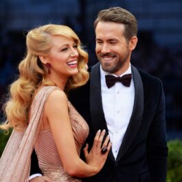 Ryan Reynolds și Blake Lively pe covorul roșu la "Charles James: Beyond Fashion", Met Gala. Reynolds e îmbrăcat într-un costum negru, cămașă albă și papion, pe când Lively are o rochie roz-aurie mulată