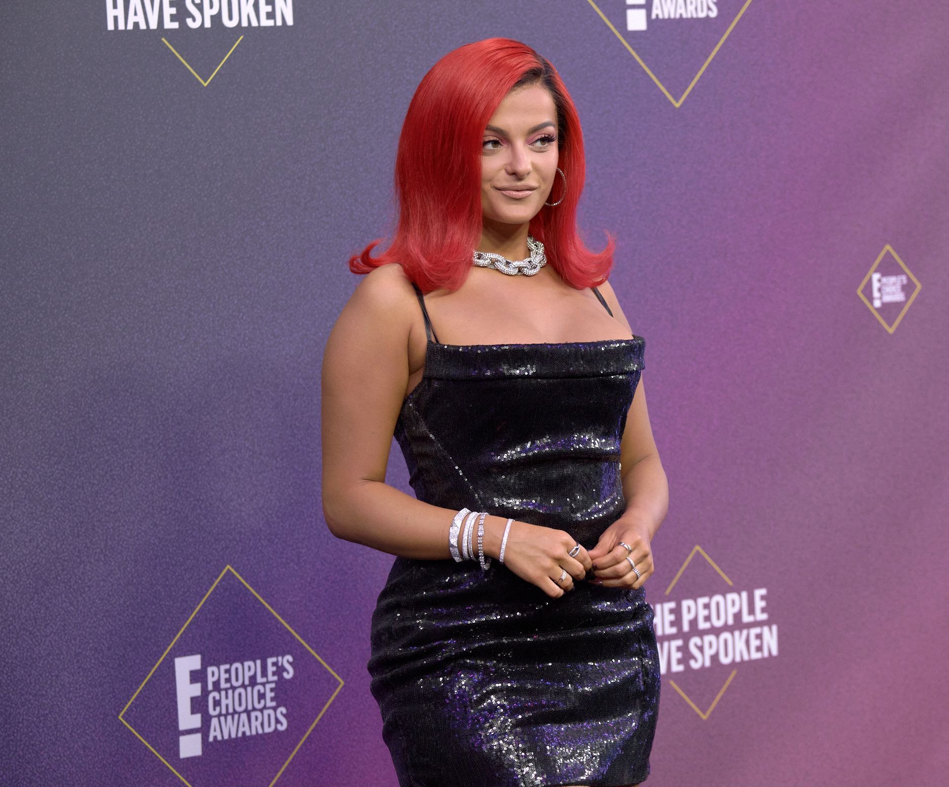 Bebe Rexha a purtat o rochie neagră, mulată, pentru People's Choice Awards, editie 46, par rosu si ondulat la varfuri, fundal mov