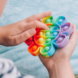 Un copil care joacă cu un pop it în formă de floare, colorat