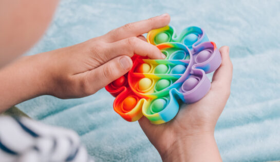 Un copil care joacă cu un pop it în formă de floare, colorat