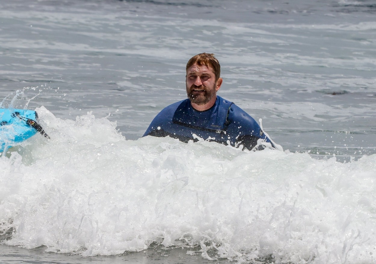 Gerard Butler, în timp ce este în valuri, pe o placă de surf, în Malibu, în 2021