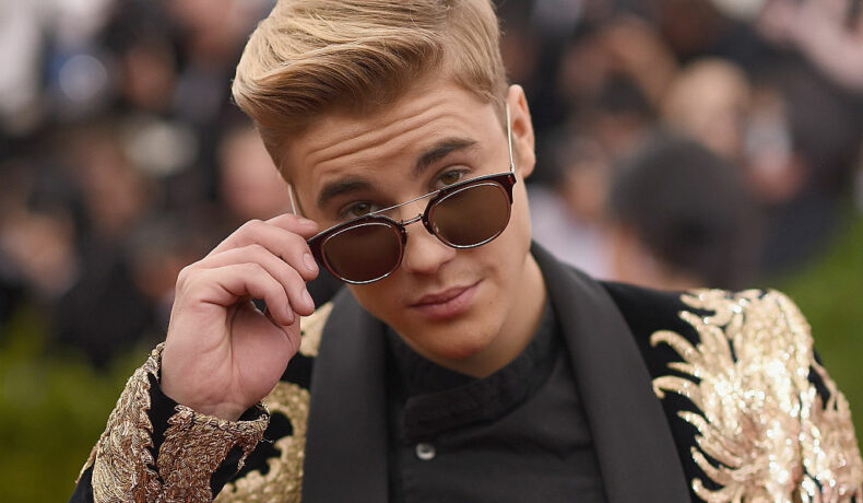 Justin Bieber, îmbrăcat într-un sacou cu aplicații, la Costume Institute Benefit Gala at the Metropolitan Museum of Art, în 2-15, în timp ce se uită peste ochelari