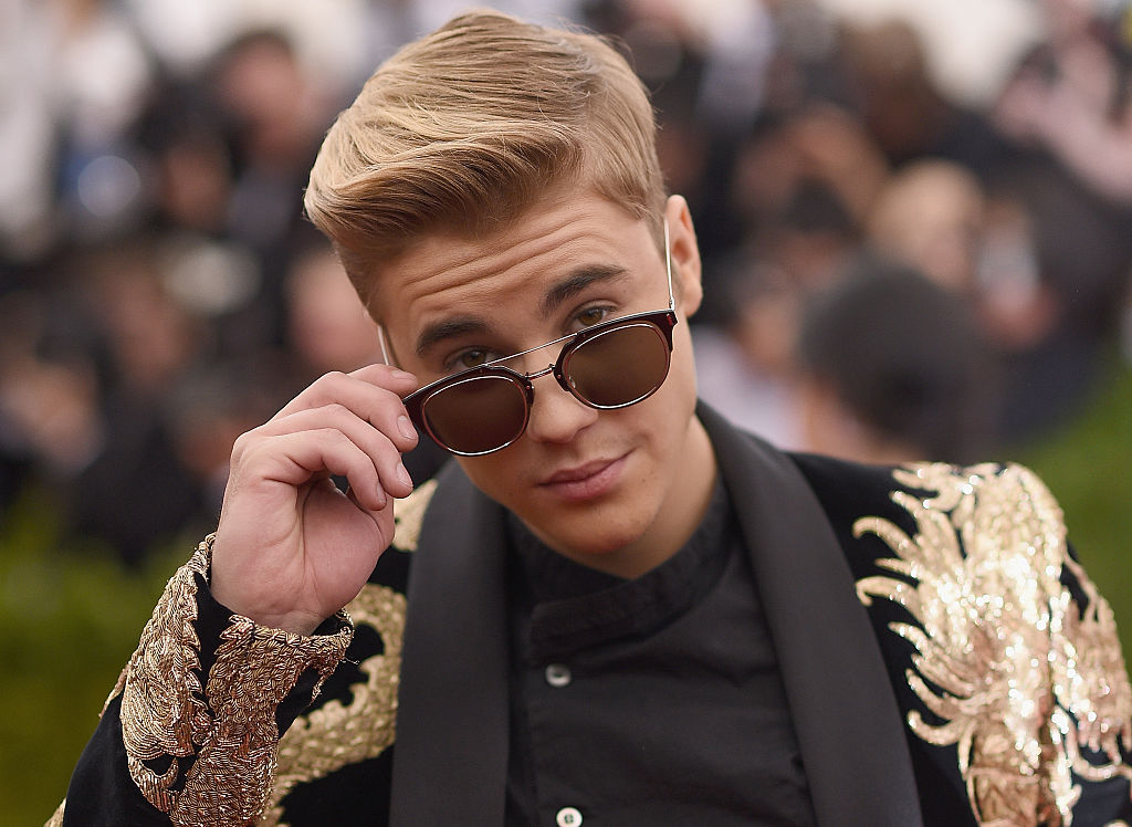 Justin Bieber, îmbrăcat într-un sacou cu aplicații, la Costume Institute Benefit Gala at the Metropolitan Museum of Art, în 2-15, în timp ce se uită peste ochelari