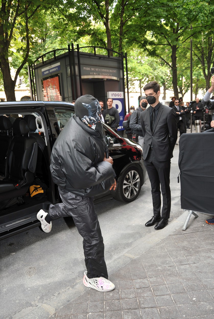 Kanye West, cu o cagulă pe cap, în timp ce iese din mașină, pentru a intra la show-ul Balenciaga 2021