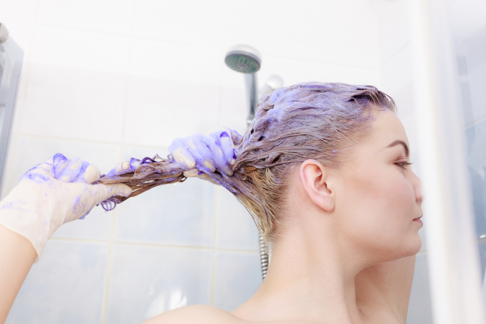 O femeie care își aplică toner pe păr la duș