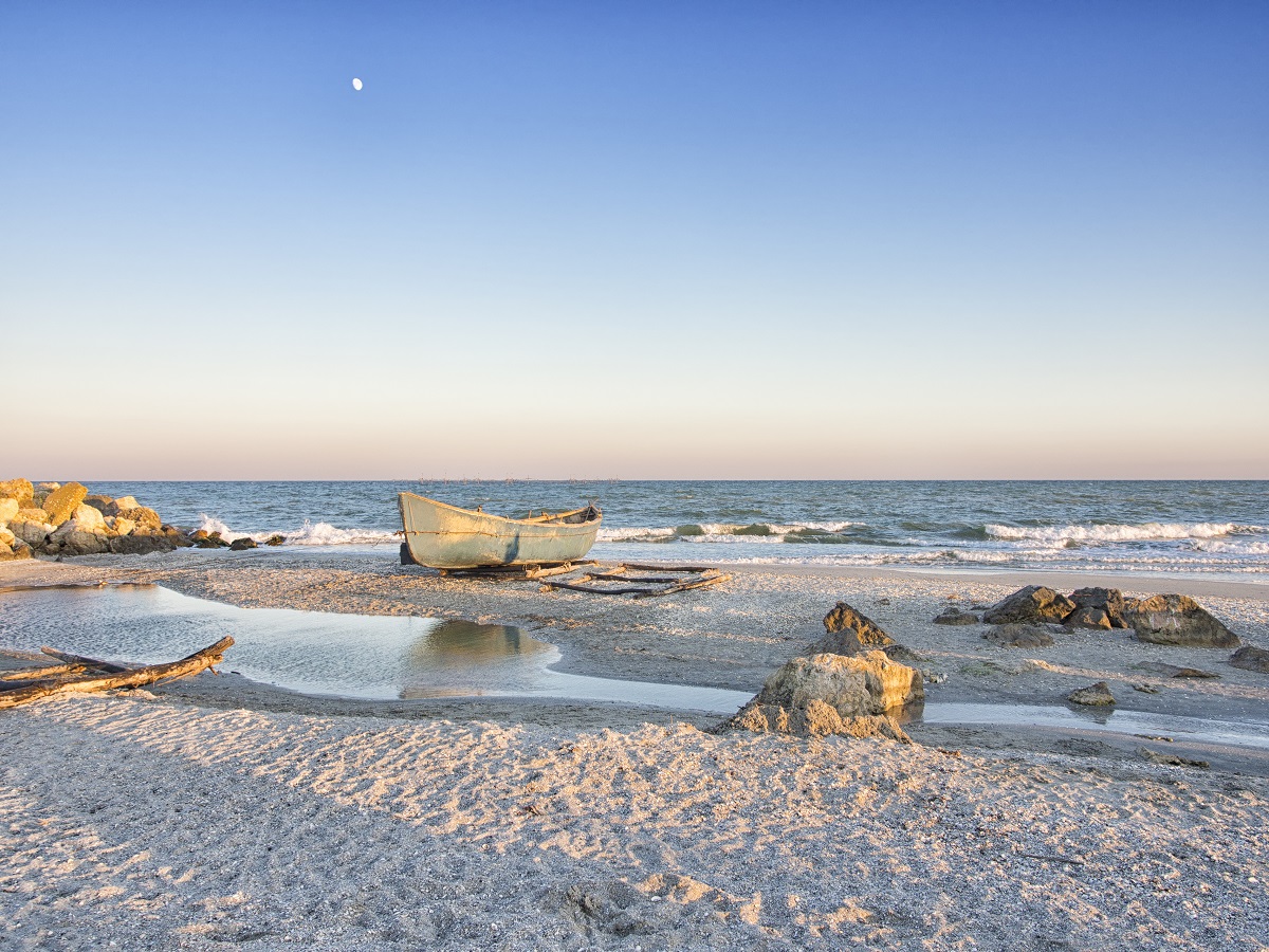 Peisaj care surprinde Plaja Corbu cu nisipul său fin și alb în timp ce este scăldată de valurile mării