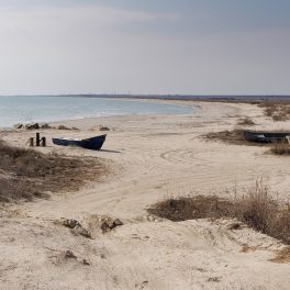 O imagine boemă în care este redată plaja Vadu cu nisipul fin și vegetația sălbatică pentru a ilustra frumusețea unei plaje mai puțin cunoscute din România
