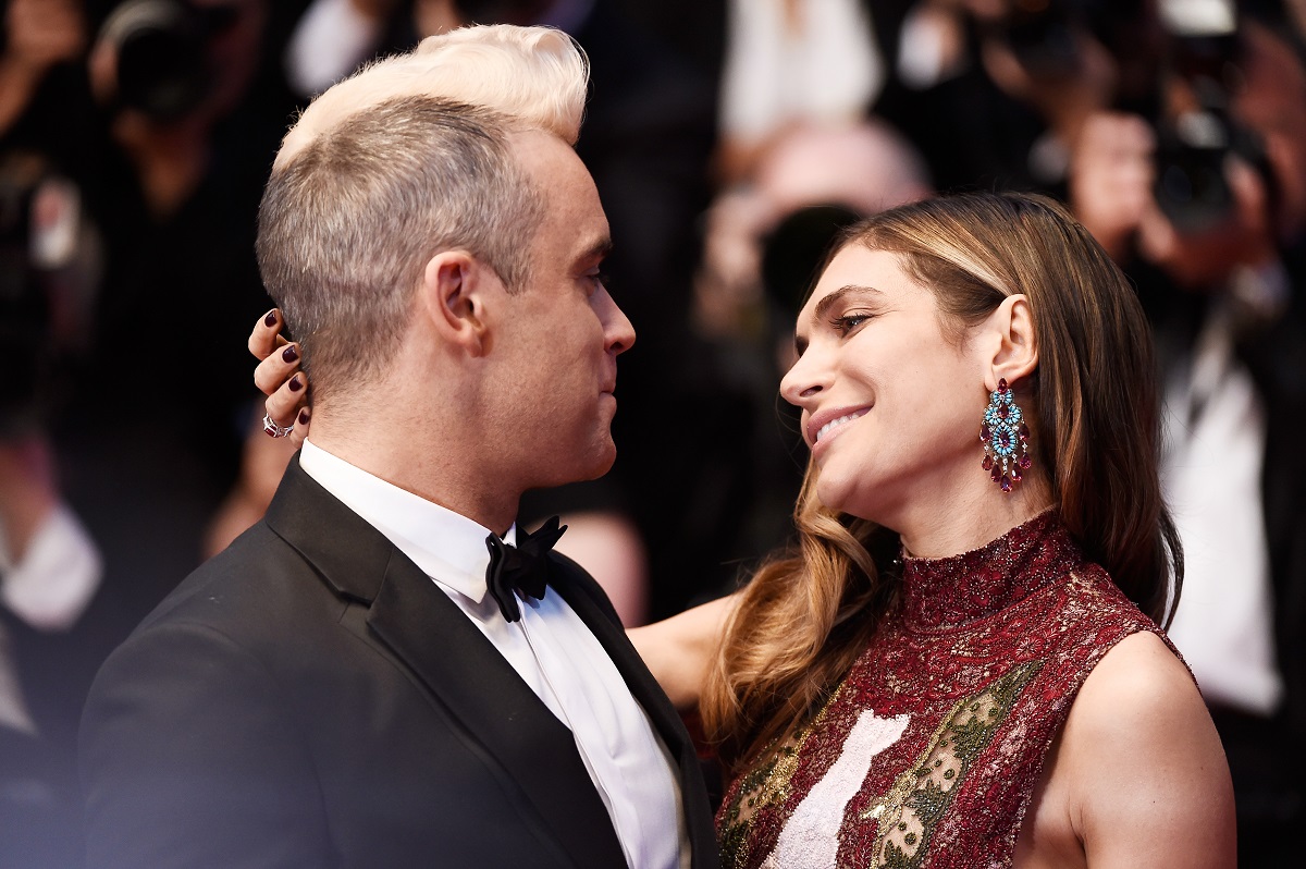 Robbie Williams și Ayda Field pe covorul roșu de la Festivalul de Film de la Cannes, 2015. S-au uitat iubitor în ochii celuilalt. El îmbrăcat în costum negru, ea în rochie roșu închis