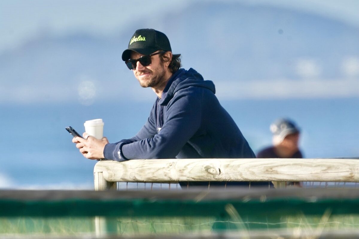 Actorul Adam Demos fotografiat după ce s-a întors în Australia în timp ce stă srpijinit de un ponton și privește în zare