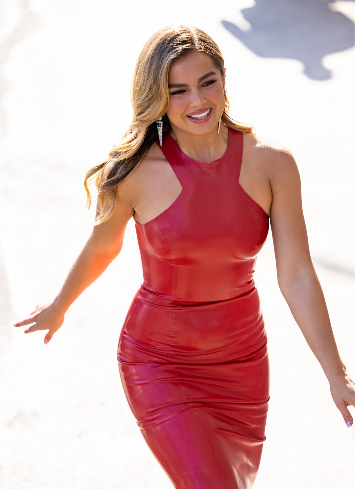 Addison Rae într-o rochie roșie mulată din latex în timp ce merge pe stradă în Los Angeles și zâmbește