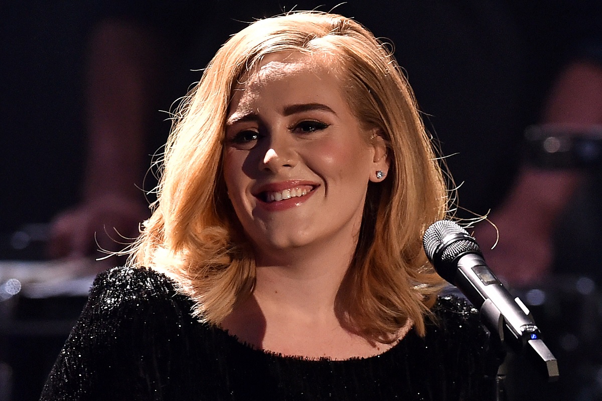 Portret al artistei Adele în timp ce zâmbește și are un față un micorfon la unul din concertele sale