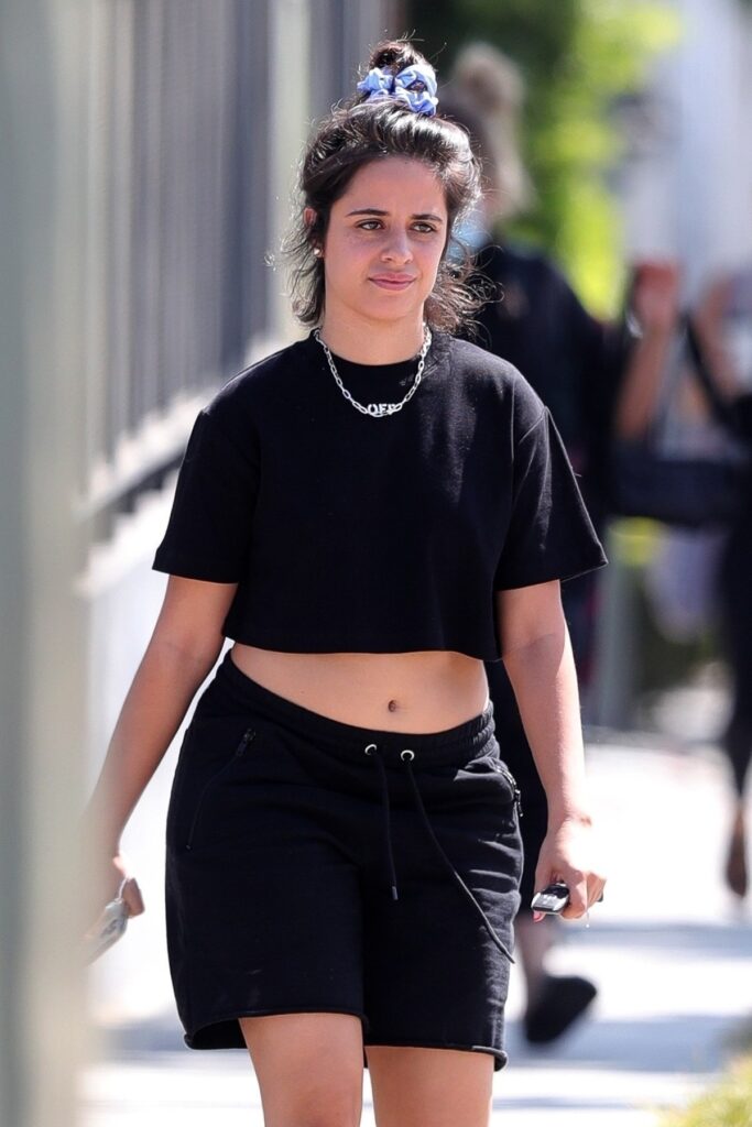 Camila Cabello într-un crop trop negru, o pereche de pantaloni scurți negri, după ce a renunțat complet la machiaj