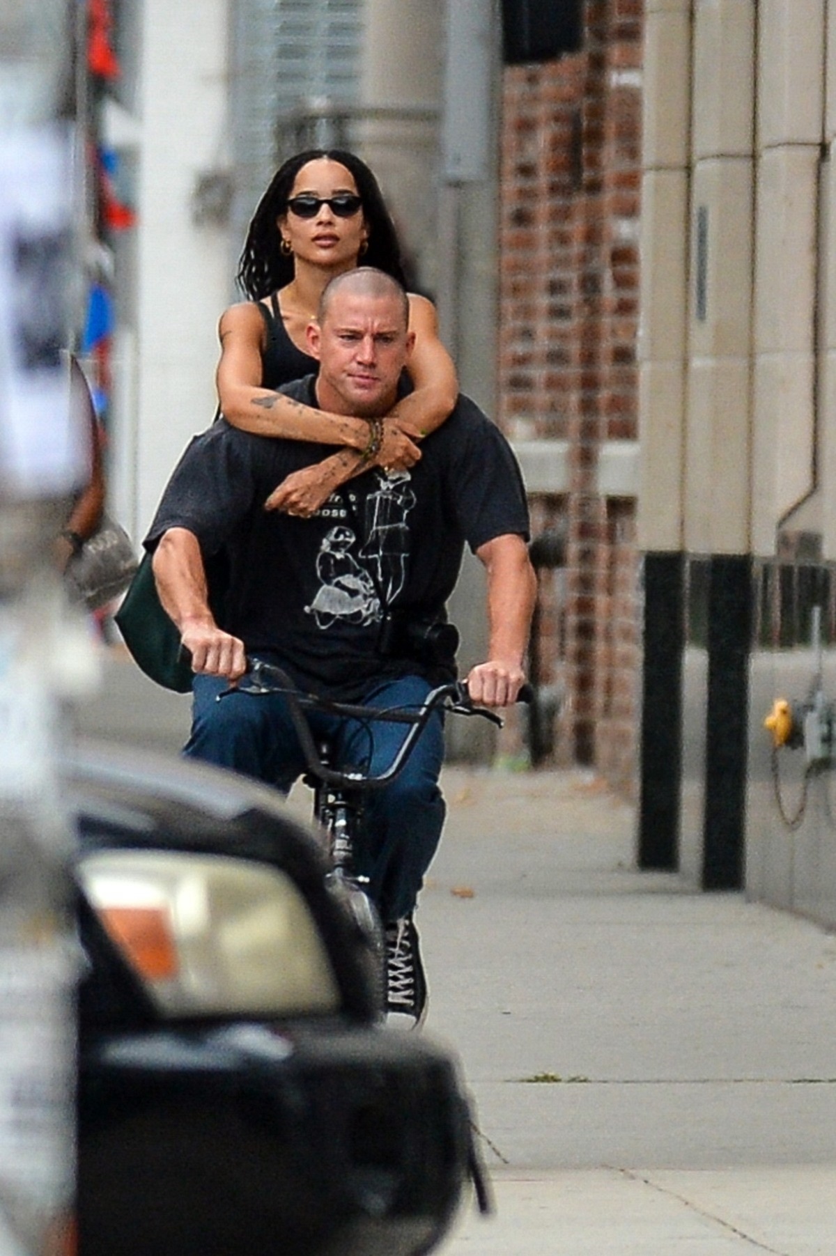 Channing Tatum într-un tricou negru și o pereche de blugi, care are o nouă iubită, în timp ce merge pe bicicletă și o ține în spate pe Zoe Kravitz