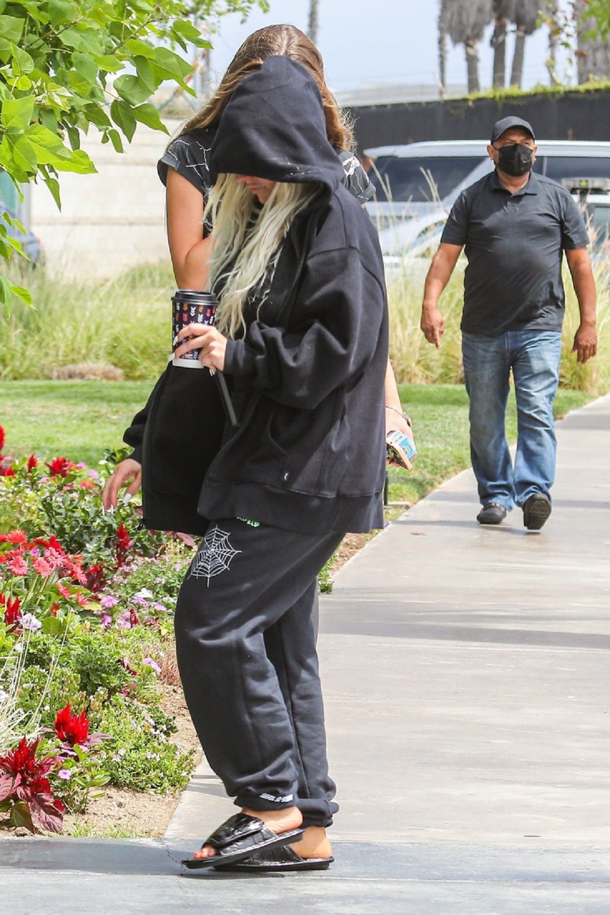 Christina Aguilera în timp ce se ascunde de fotografi și poartă un hanorac negru cu glugă pe cap și o pereche de pantaloni de trening