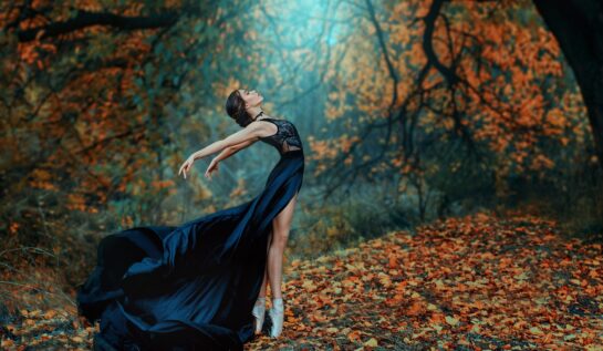 O femeie frumoasă balerină într-o rochie neagră în timp ce dansează balent într-o pădure