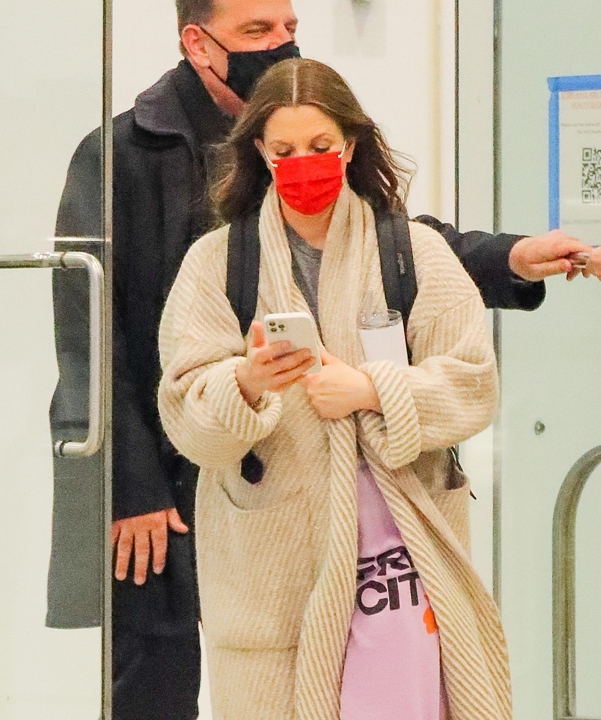 Drew Barrymore înt-un aeroport purtând o mască roșie și o haină de blană crem
