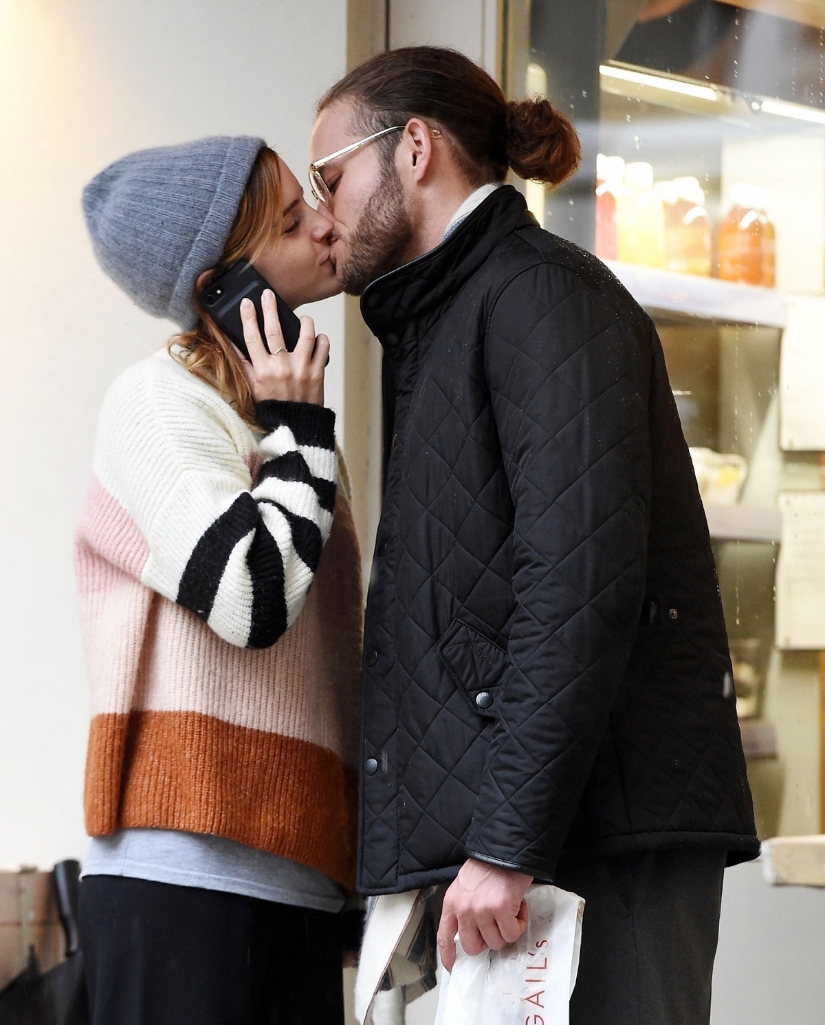Emma Watson în timp ce poartă un pulover în dungi și o căciulă pe cap, sărutându-l pe iubitul său, Leo Robinton