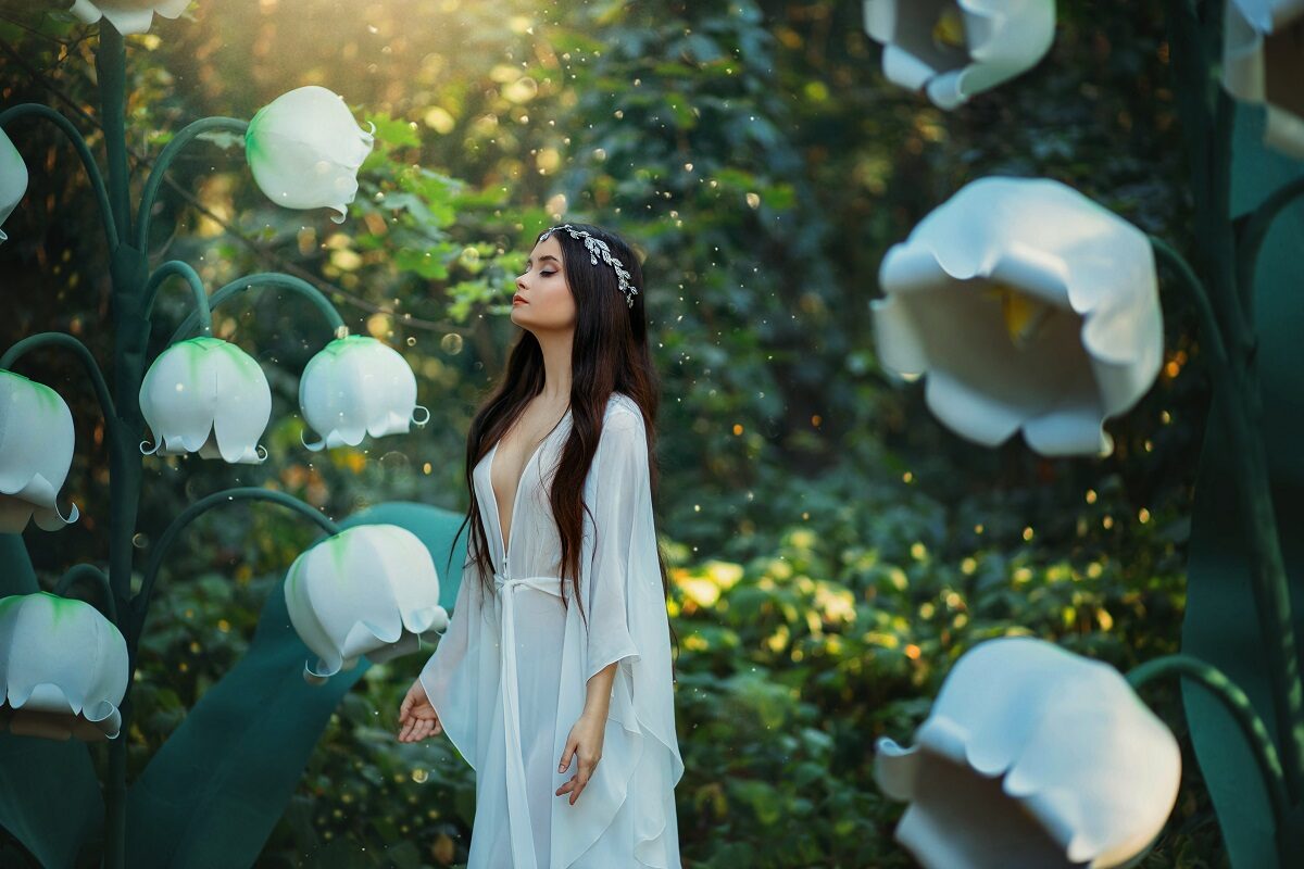 O femeie frumoasă îmbrăcată întro rochie albă în timp ce se află într-o pădure printre flori albe și se gândește care sunt acele gesturi pe care zodiile de aer le adoră într-o relație