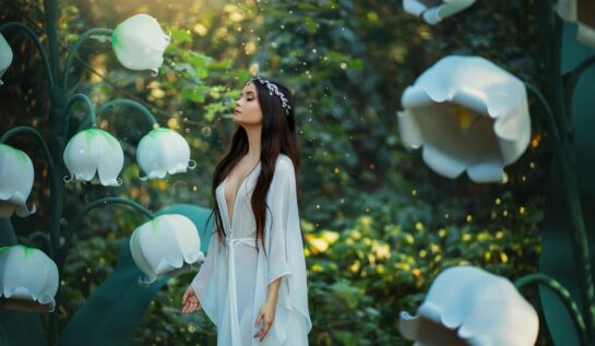 O femeie frumoasă îmbrăcată întro rochie albă în timp ce se află într-o pădure printre flori albe și se gândește care sunt acele gesturi pe care zodiile de aer le adoră într-o relație