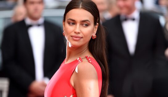 Portret al fotomodelului Irina Shayk în timp ce privește peste umăr într-o rochie roșie la festivalul de film de la Cannes din 2018