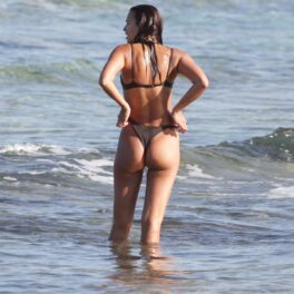 Irina Shayk fotografiată cu spatele în timp ce își așează costumul de baie maro