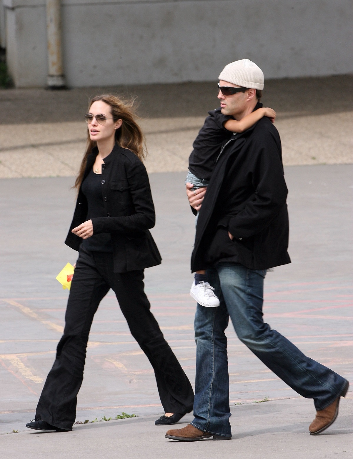 Angelina Jolie îmbrăcată în negru alături de fratele său, James Haven Voight care îl ține în brațe pe fiul actriței Maddox