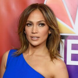 Portret al vedetei Jennifer Lopez în timp ce poartă o rochie pe umăr albastră și privește la cameră la NBCUniversal Press Tour din 2016