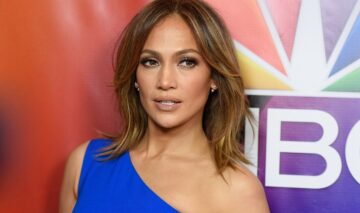 Portret al vedetei Jennifer Lopez în timp ce poartă o rochie pe umăr albastră și privește la cameră la NBCUniversal Press Tour din 2016