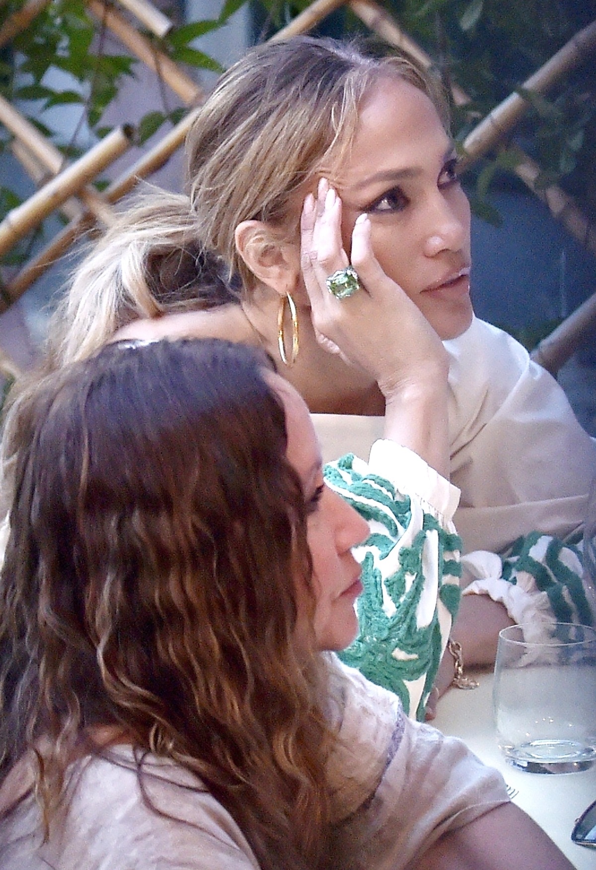 Vedeta Jennifer Lopez în timp ce stă la o masă și își sprijină fața în palme