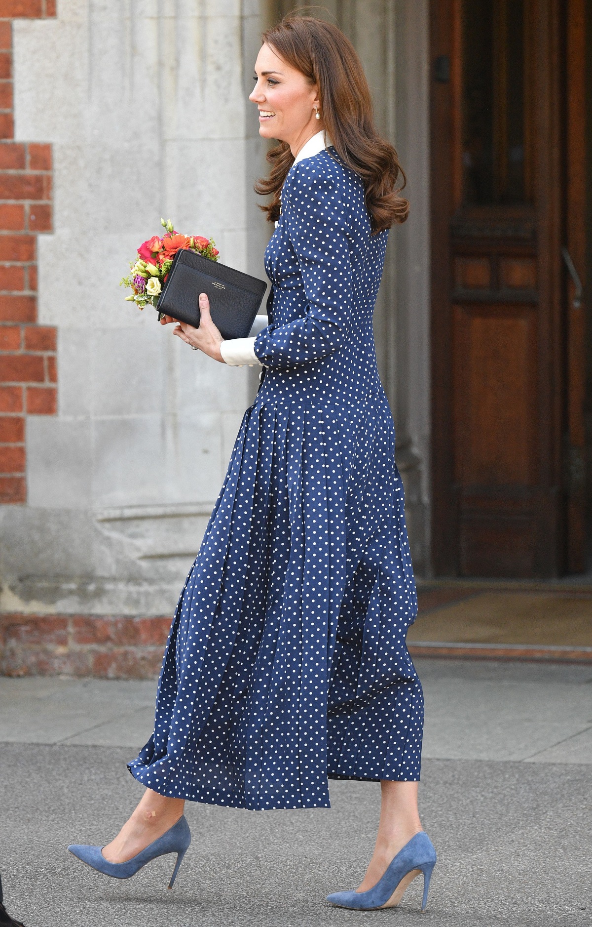 Kate Middleton în timp ce merge și poartă o rochie albastră cu buline albe la o plimbare prin parcul Bletchley