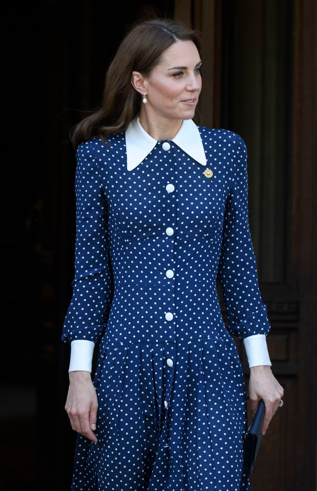 Kate Middleton purtând o rochie albastră cu buline albe în timp ce se plimbă pe stradă