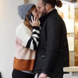 Leo Robinton într-o geacă neagră cu părul prins într-un coc în timp ce o sărută pe frunte pe iubita sa Emma Watson