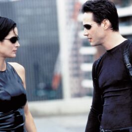 Keanu Reeves și Carrie-Anne Moss îmbrăcați în ținute negre într-o scenă din filmul Matrix din 1999