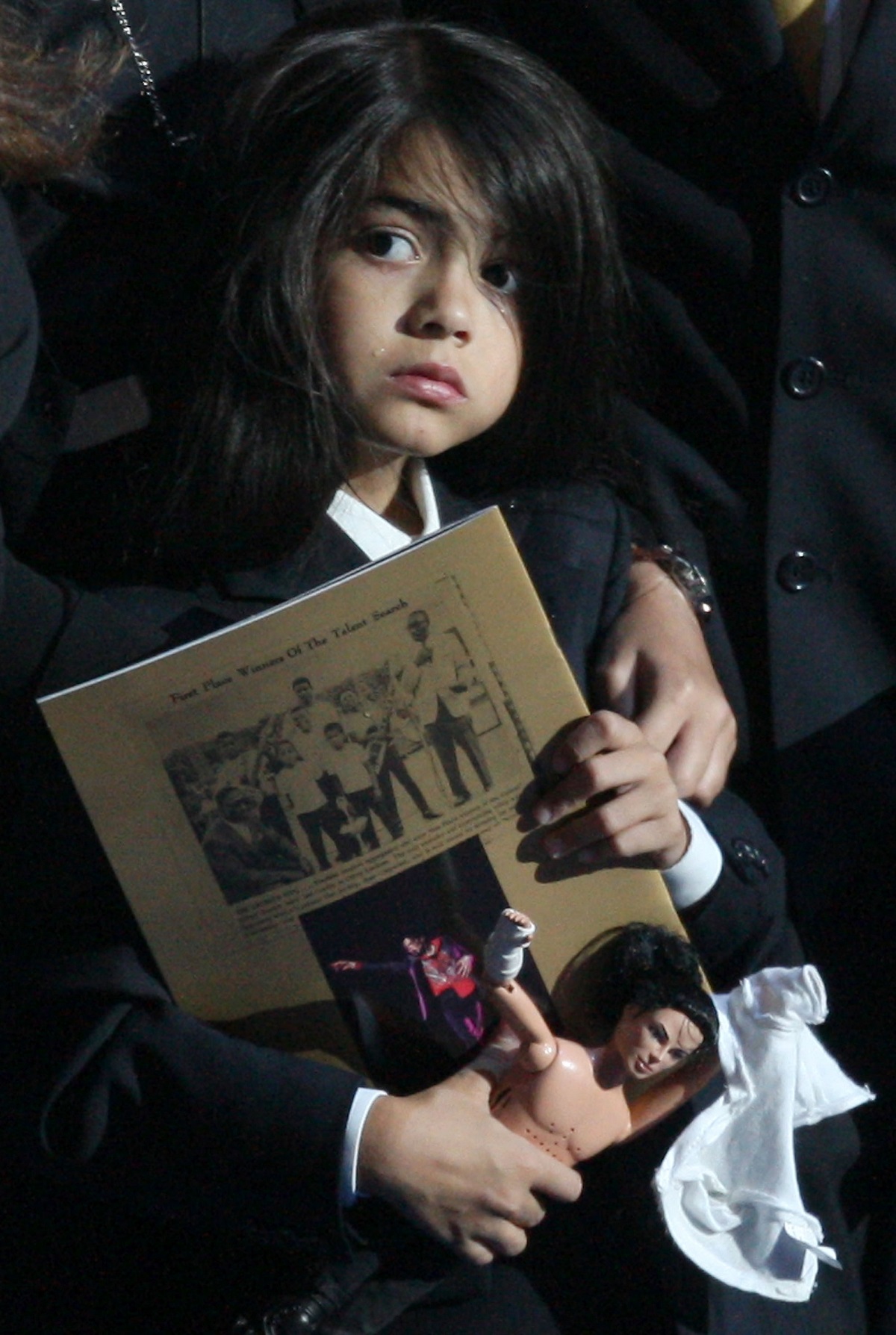 Prince Michael Blanket Jackson II, în timp ce ține în mână o revistă la ceremonia de înmormântare a tatălui său, Michael Jackson din 2009