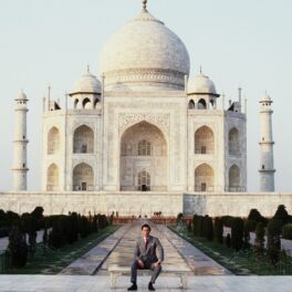 Prințul Charles îmbrăcat la costum în timp ce stă pe o bancă în fața monumentului de la Taj Mahal