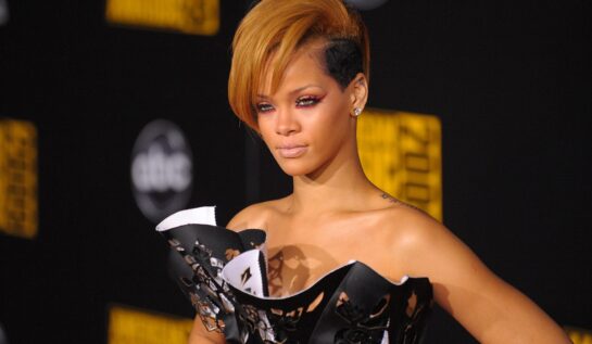 Portret al artistei Rihanna având părul tuns scurt și vopsit blond în timp ce pozează pe covorul roșu la American Music Awards din 2009