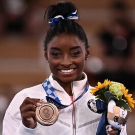 Gimnasta Simone Biles în timp ce ține în mână un buchet de flori și o medalie de argint în cadrul Jocurilor Olimpice de la Tokyo