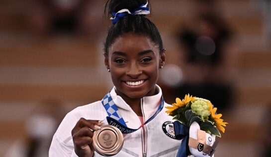 Gimnasta Simone Biles în timp ce ține în mână un buchet de flori și o medalie de argint în cadrul Jocurilor Olimpice de la Tokyo