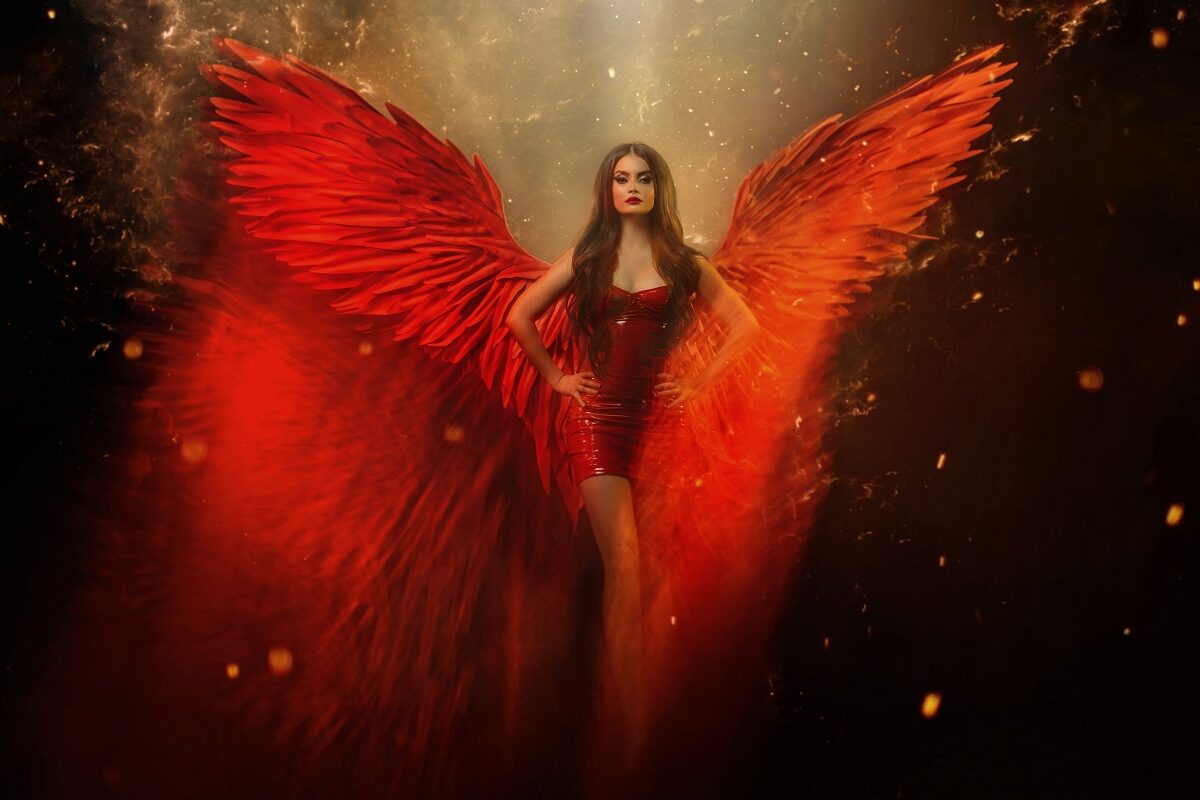 O femeie frumoasă într-un cadru întunecat în timp ce poartă o rochie roșie și o pereche de aripi roșii pentru a simboliza una dintre acele zodii extrem de încrezătoare