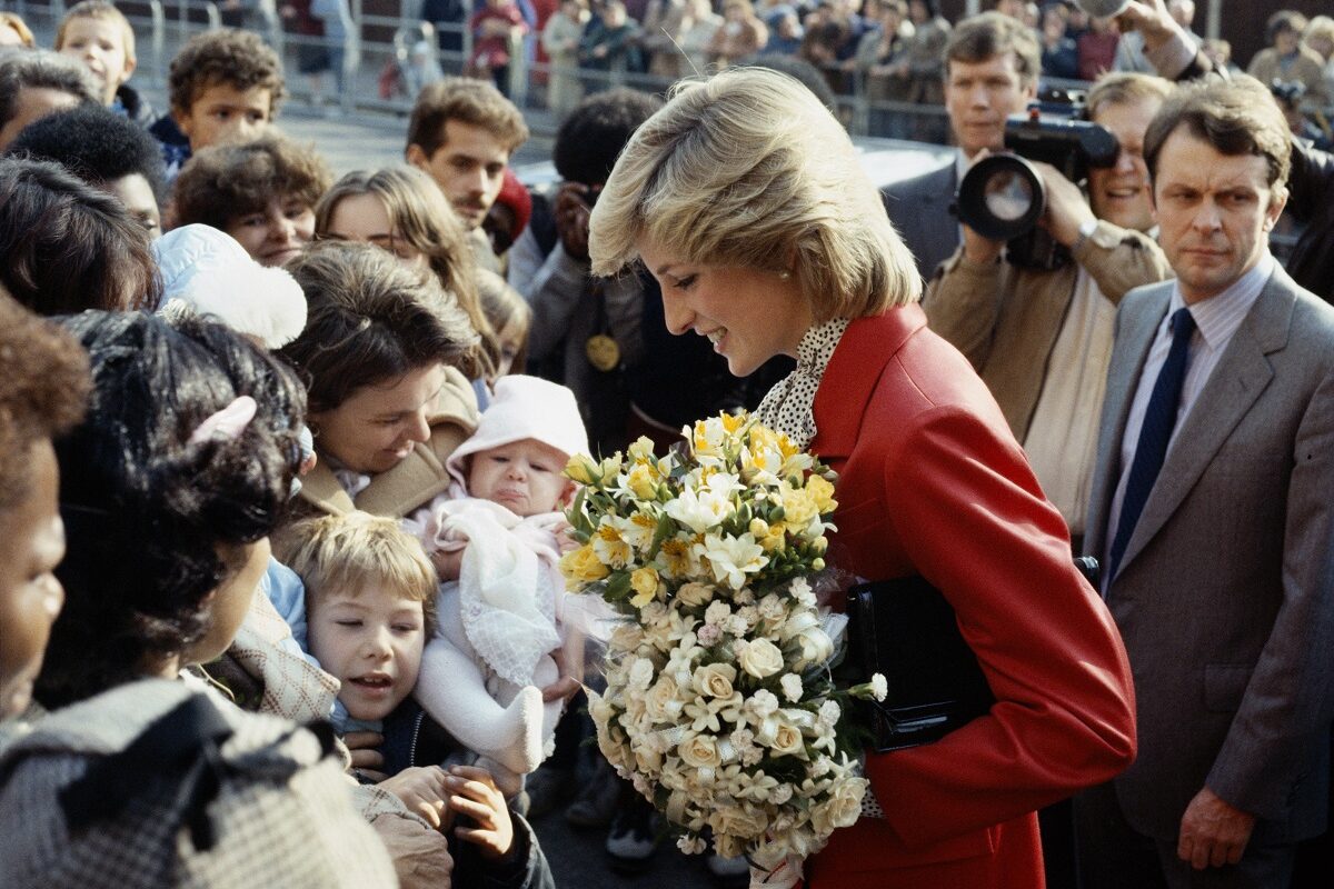 Într-o vizită în Brixton, 1982, Prințesa Diana a purtat un osum roșu pe care le-a accesorizat cu o geantă neagră. Surprinsă în mulime, cu buchete de flori în mână
