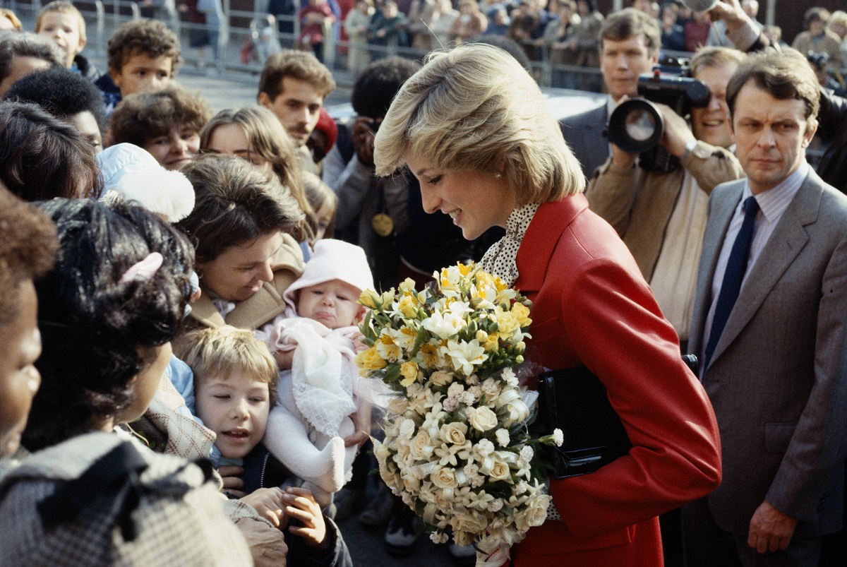 Într-o vizită în Brixton, 1982, Prințesa Diana a purtat un osum roșu pe care le-a accesorizat cu o geantă neagră. Surprinsă în mulime, cu buchete de flori în mână
