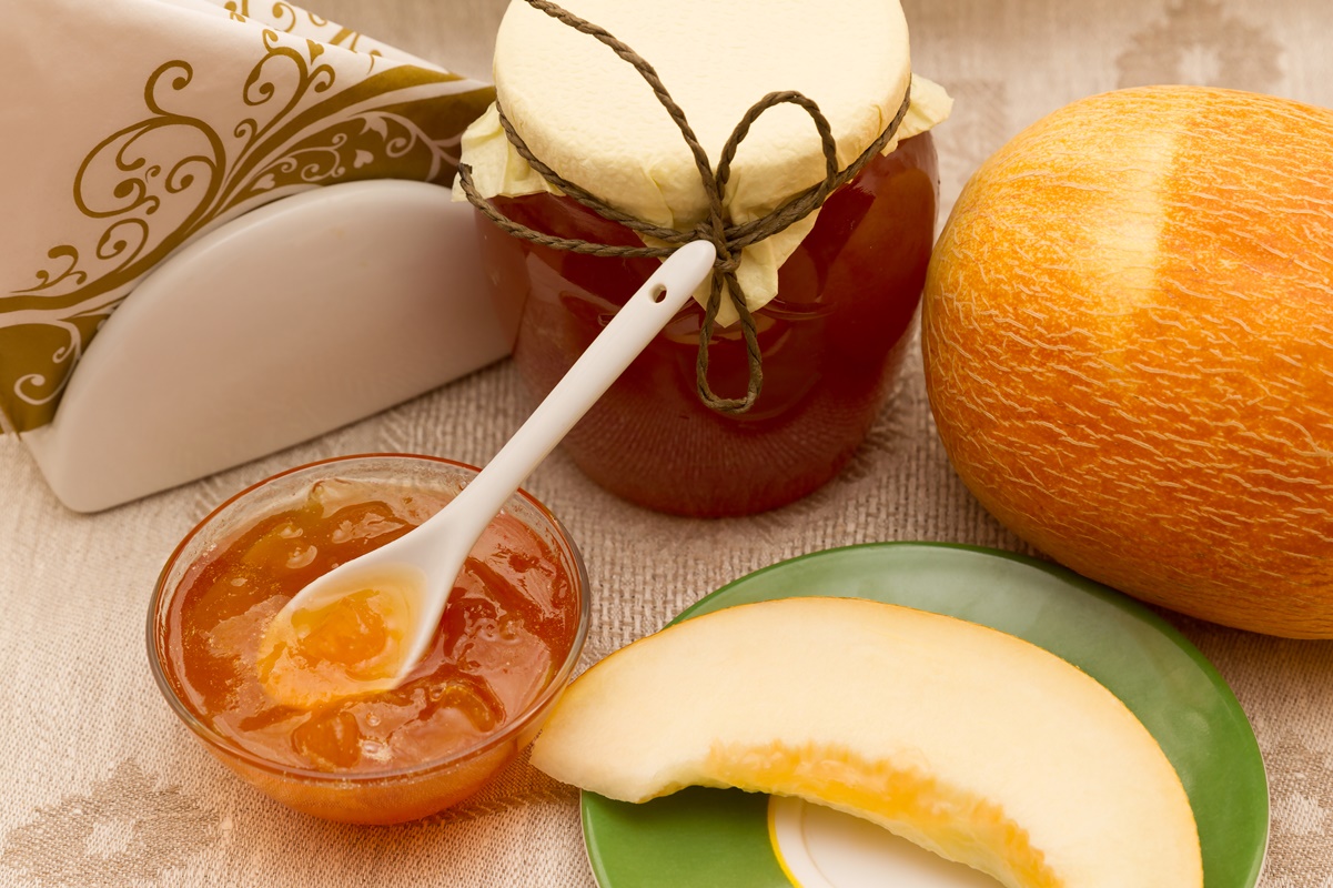 Dulceață de pepene galben cu ghimbir, într-un bol de servire și în borcan, alături de un pepene galben și o felie de pepene