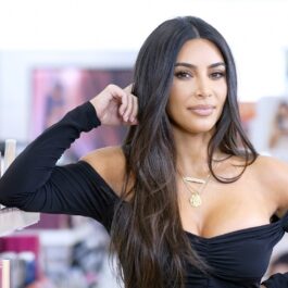 Kim Kardashian la lansarea KKW Beauty în octombrie 2019. Fundal din magazinul Ulta, Kim Kardashian poartă o rochie neagrp, mulată, cu mâneci, decolteu, fără umeri, părul lung