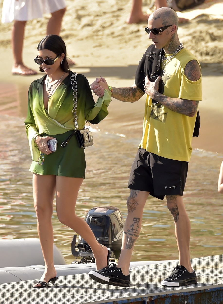 Travis Baker o ține de mână pe Kourtney Kardashian și se îndreaptă spre o plajă din Italia