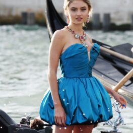 Leni Klum, fiica lui Heidi Klum, la prezentarea de modă Dolce & Gabbana Alto Moda, din Veneția, august 2021. Ea a purtat o rochie albastră, cu corset, scurtă și cu decolteu. A accerosizat-o cu o coroană și diamante colier. Pe gondolă, cu fundal cu apă și bărci