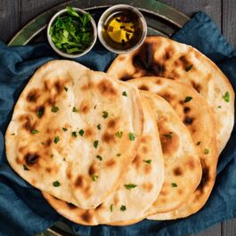 5 porții de pâine indiana Naan preparată la tigaie, alături de 2 boluri cu ingrediente pentru servit
